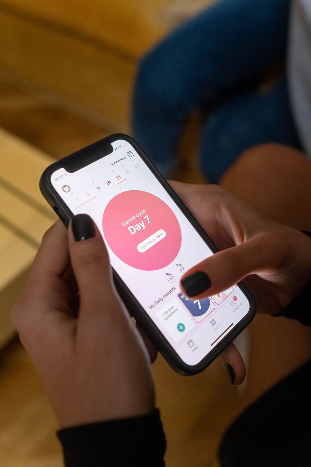 Hands holding a phone open on a period-tracking app