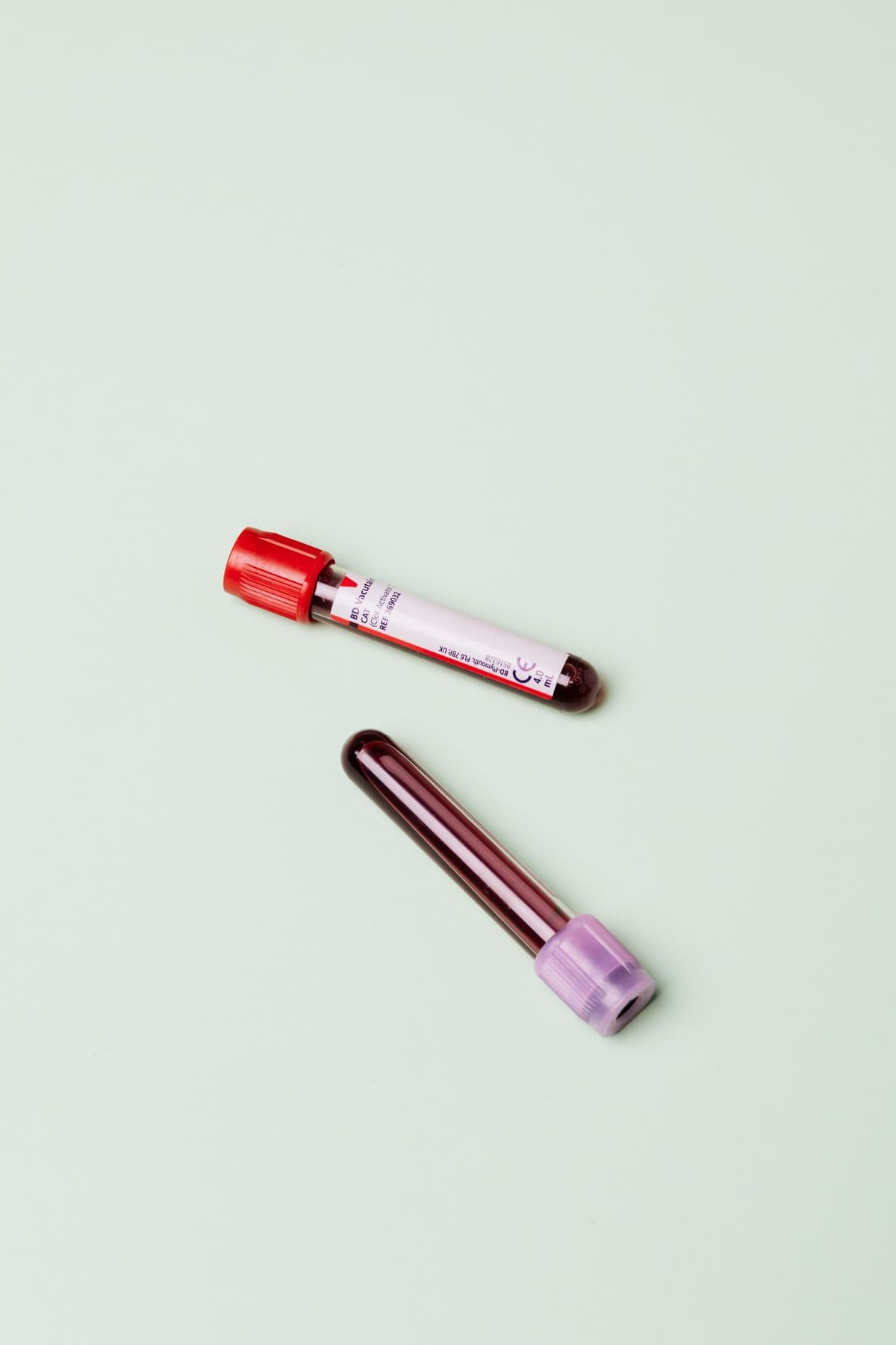 Two blood sample tubes on a pale green background