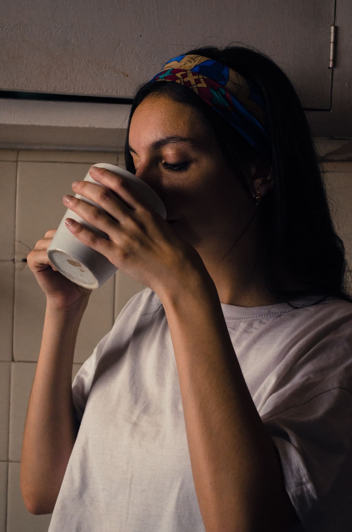 A woman with her eyes closed, sipping from a mug