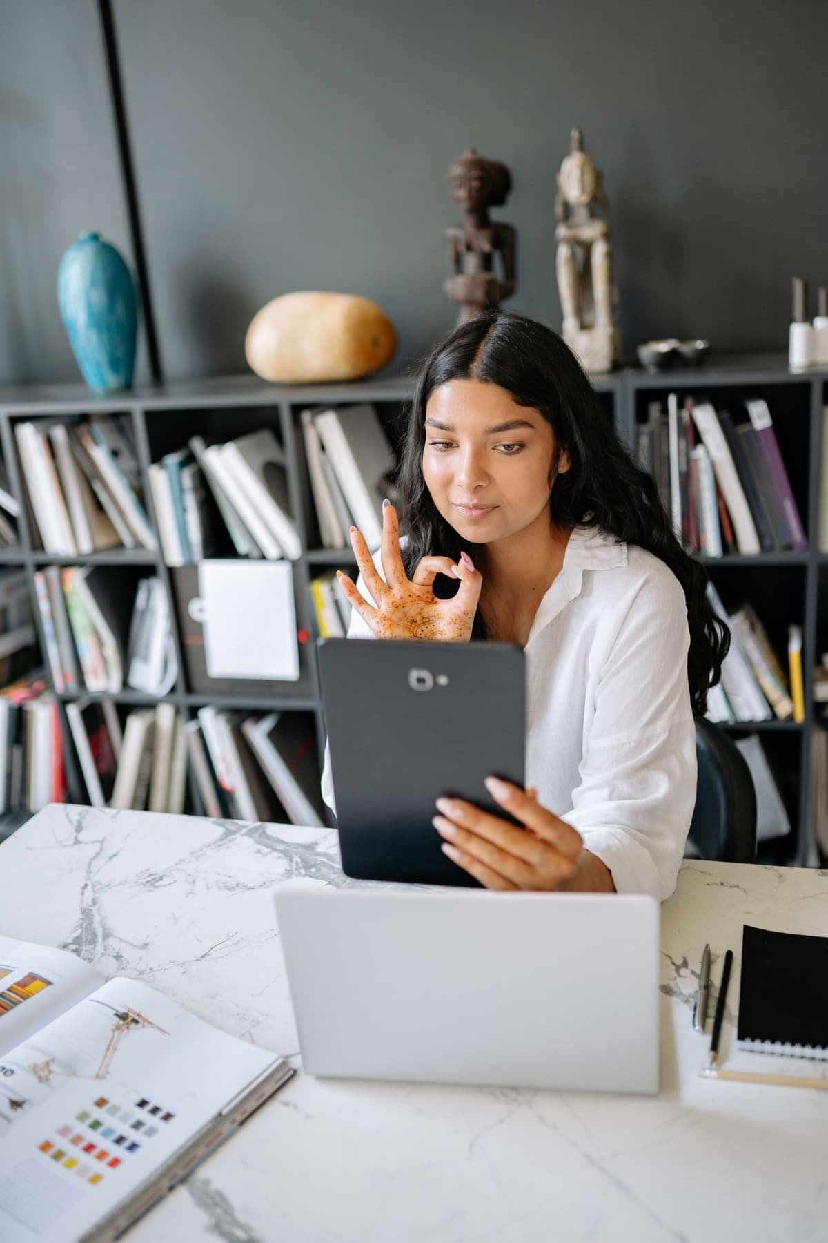 A young Indian woman on a video call on her tablet at her desk