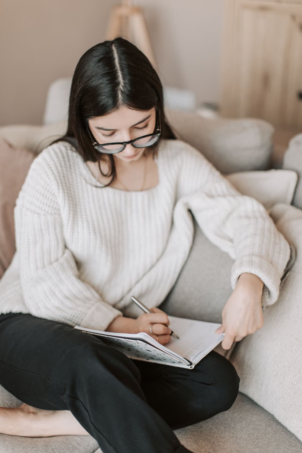 A young woman in glasses writing in a notebook