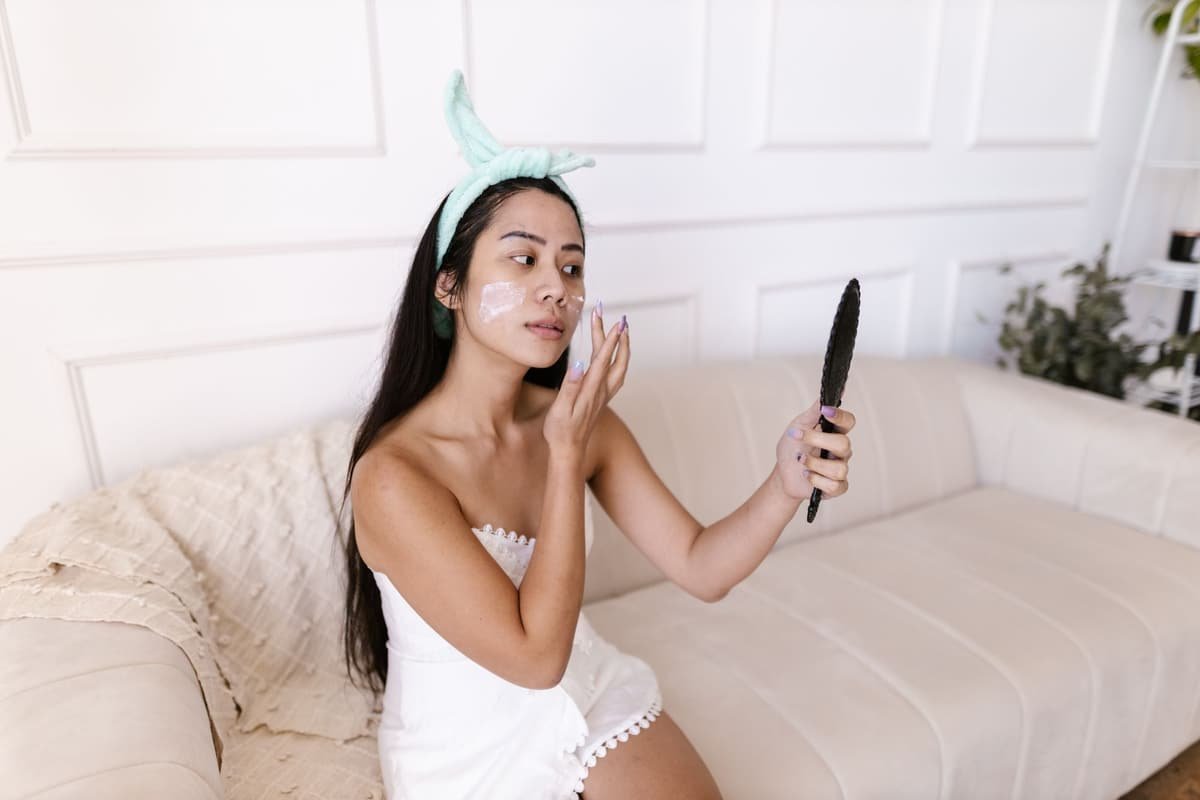 A young woman checking her skin in a hand mirror