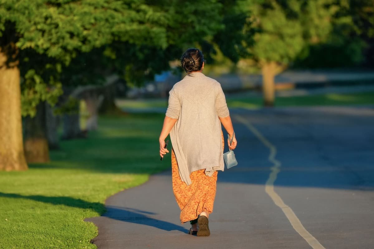 A woman in a kurta walking along a park path
