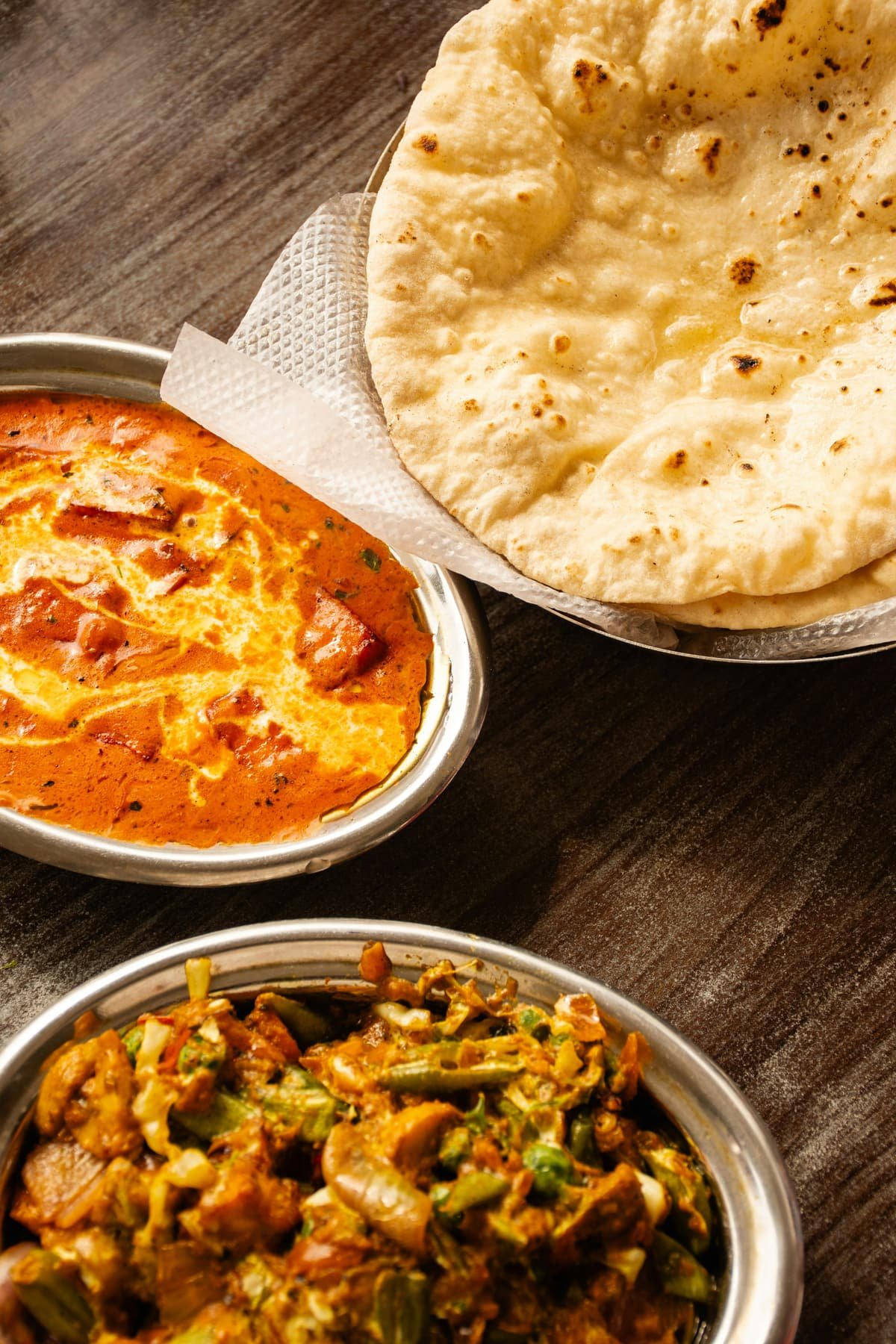 Bowls of curry and sabzi served with roti
