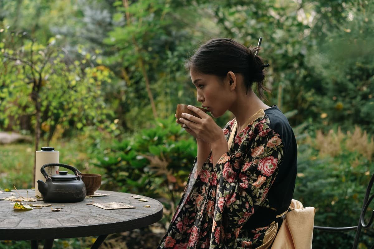 A woman sipping tea at a garden table